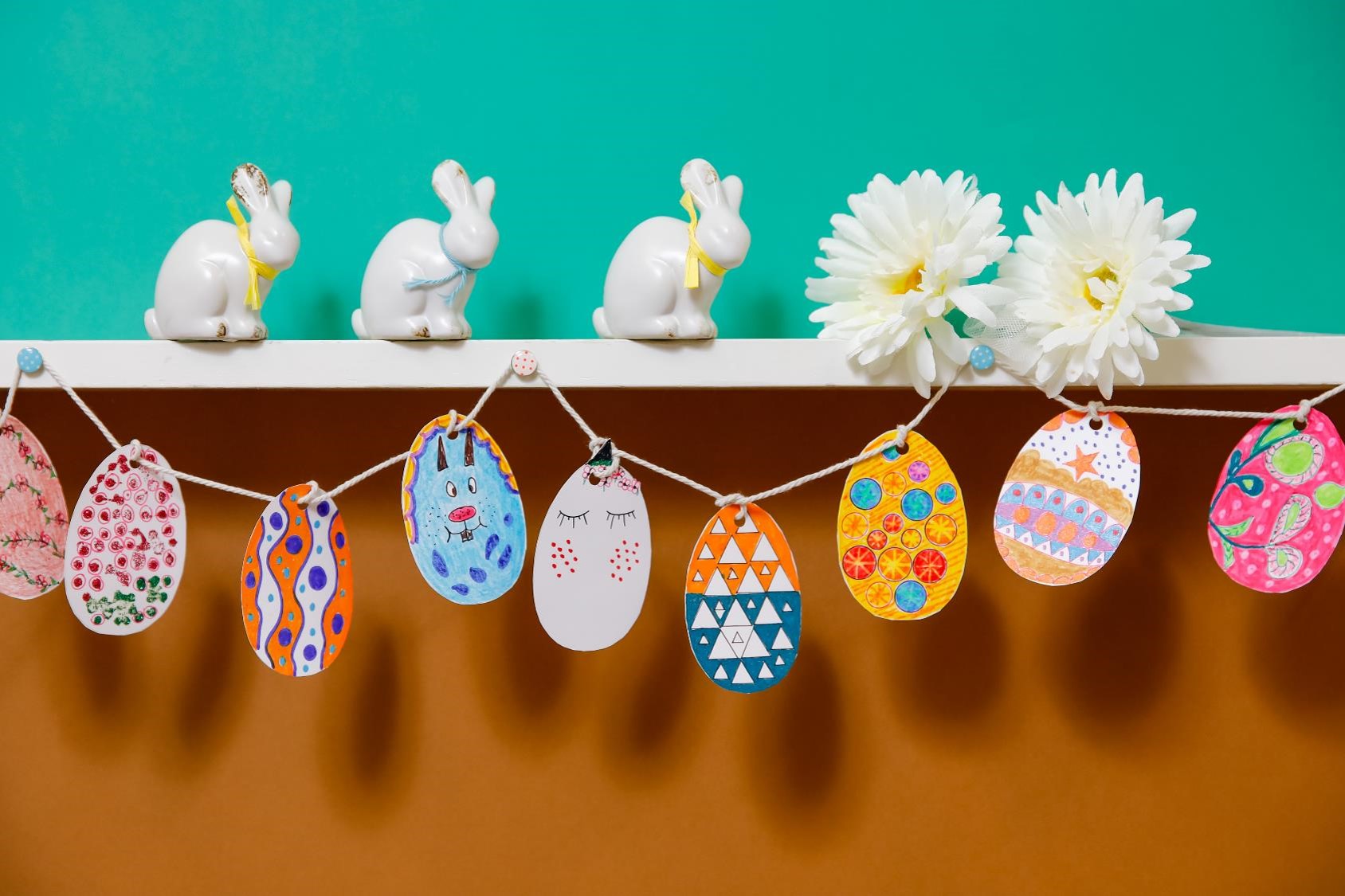 Easter bunting hung on a shelf with bunnies and flowers