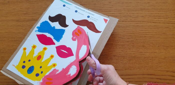 A hand cutting out coloured photo booth templates