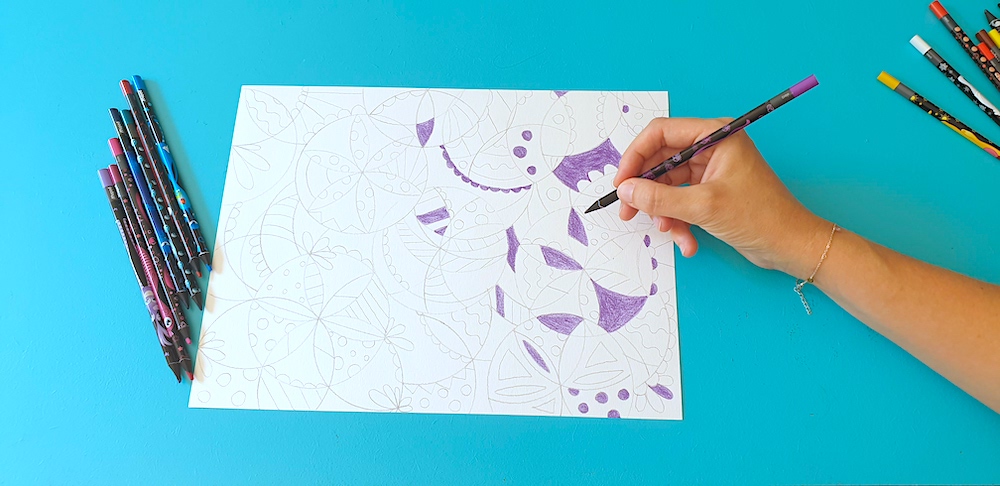 A hand colouring in a patterned sheet