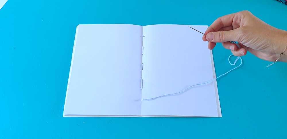 an open note book with a needle and thread