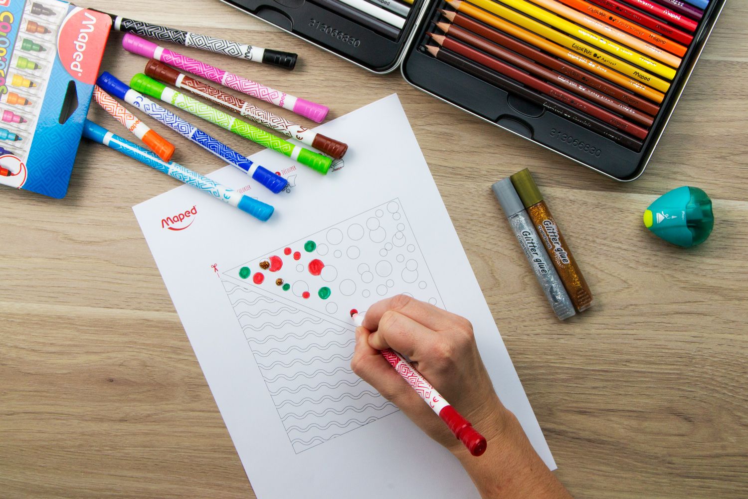 a hand colouring in templates for pouches with felt tips lay on the table