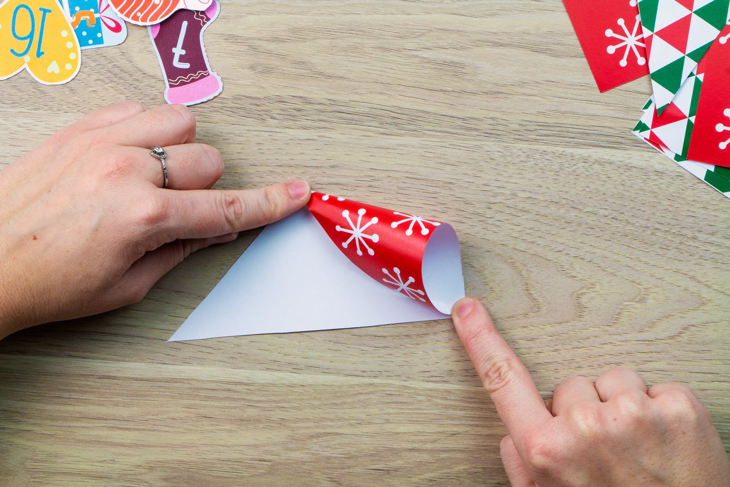 two hands rolling up a piece of patterned paper to create a pouch