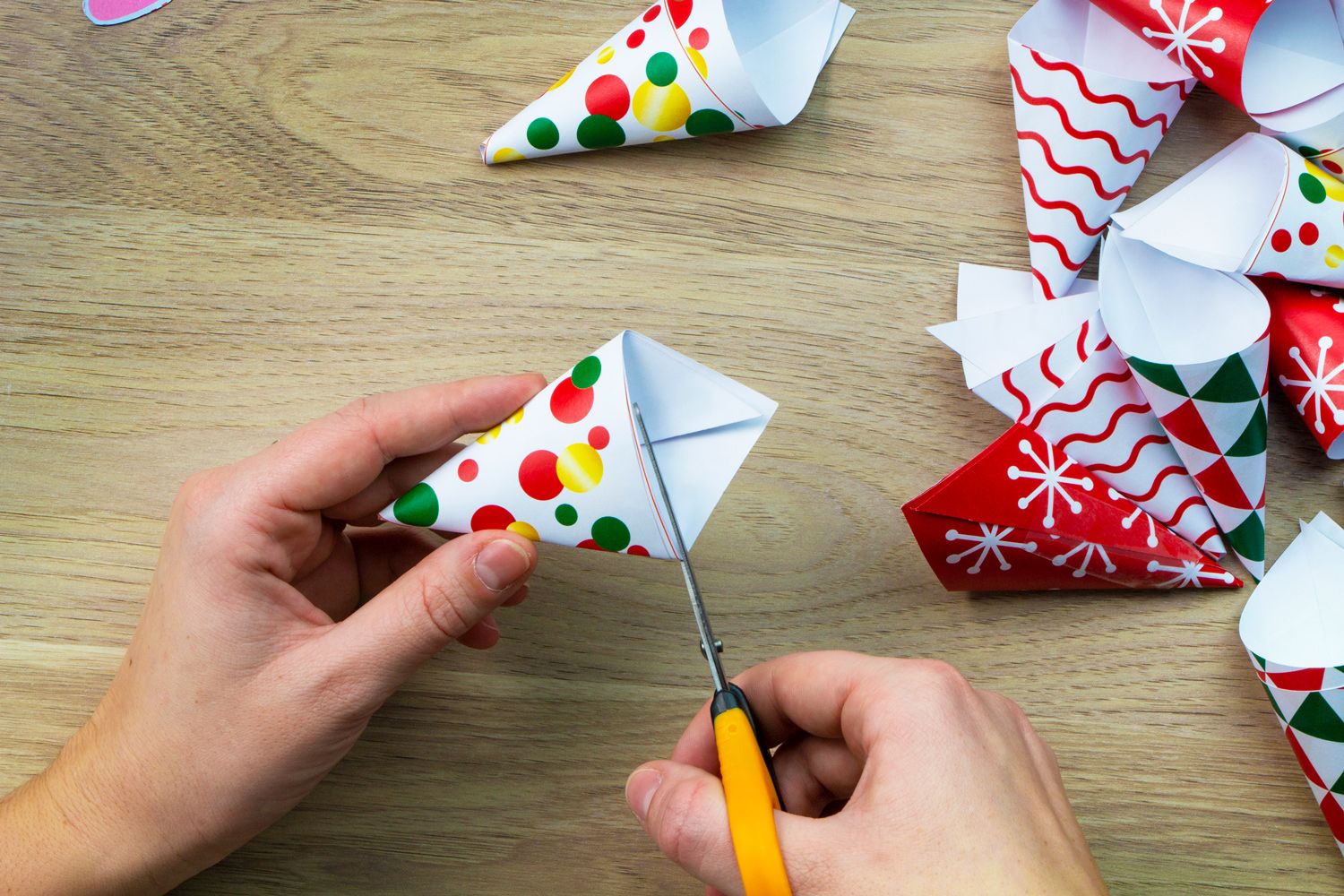 A hand holding scissors cutting out a coloured pouch