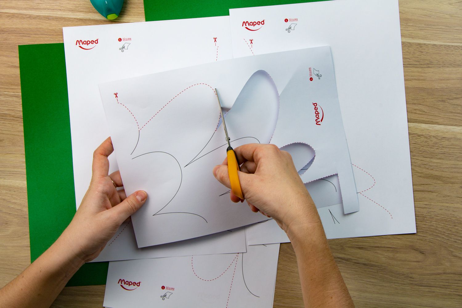 A hand and scissors cutting out a template