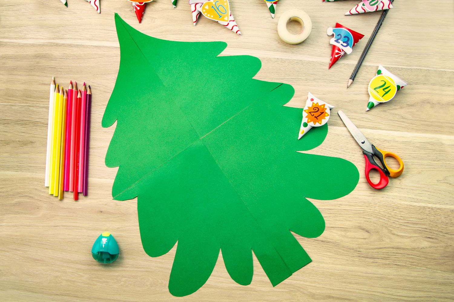 A green Christmas tree outline with stationery laying on a desk