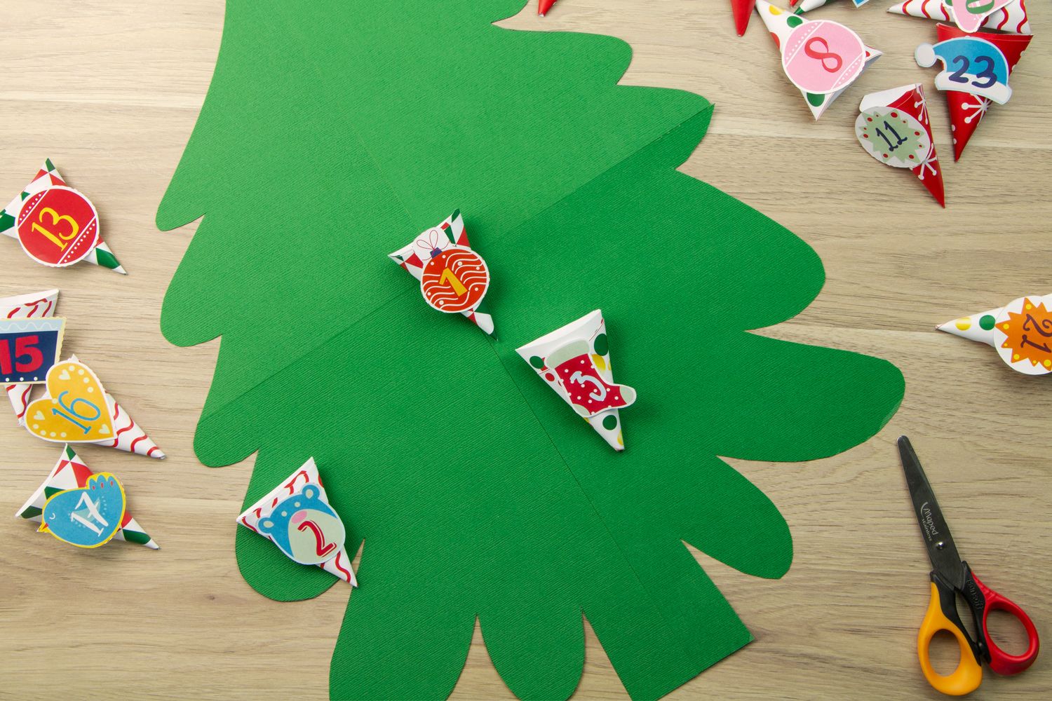 a green Christmas tree outline with homemade numbered pouches surrounding