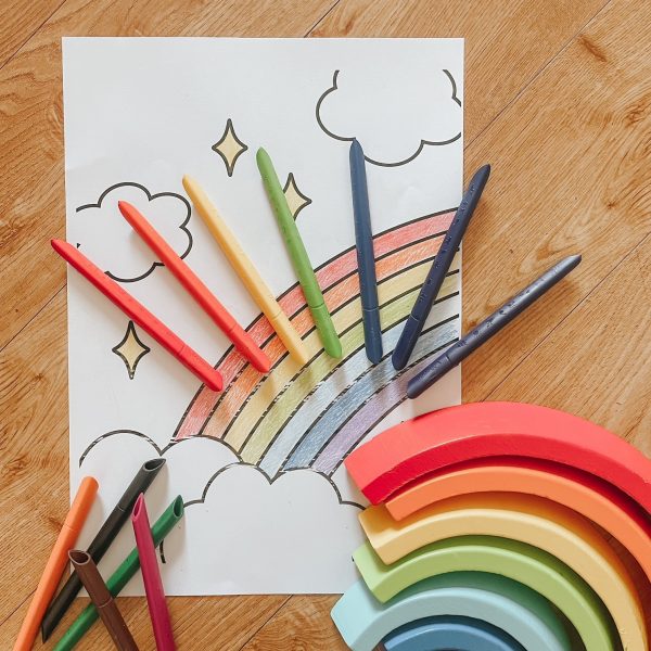 A picture of a rainbow colouring with infinity colouring pencils on top of the paper