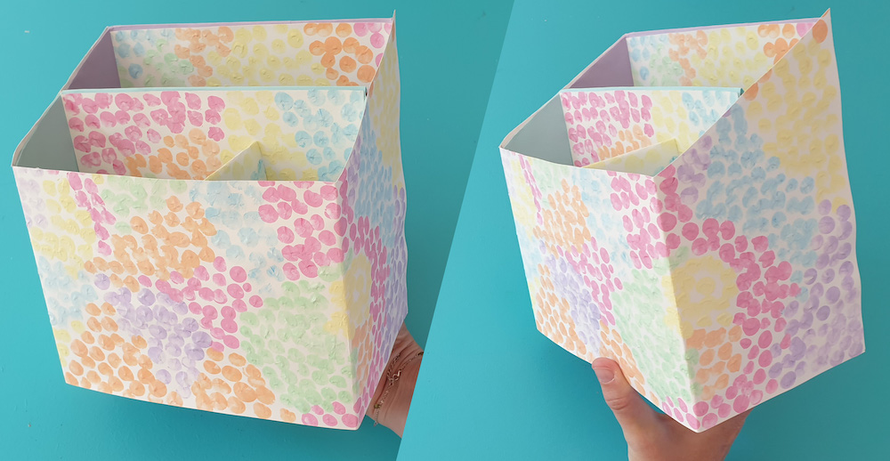 Two cereal boxes stuck together with the tops cut off decorated with paper covered in coloured spots