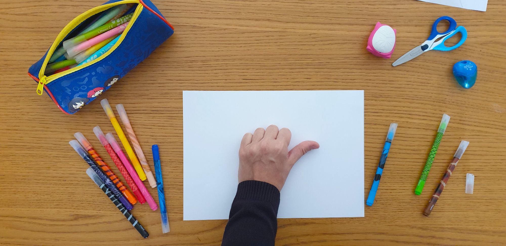 A closed hand placed on a sheet of paper surrounded by stationery