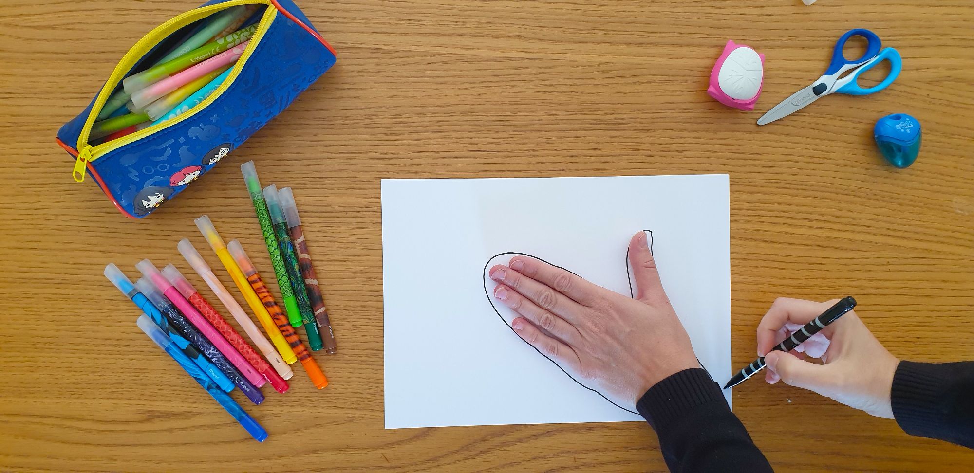 An open hand placed on a sheet of paper surrounded by stationery