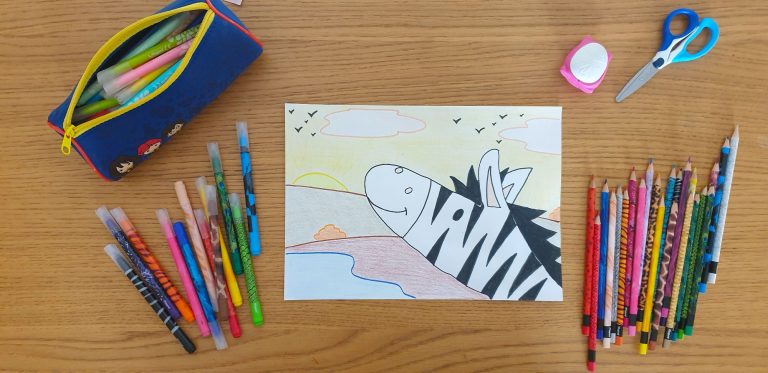 A piece of paper with a drawing of a zebra laying on a desk surrounded by stationery