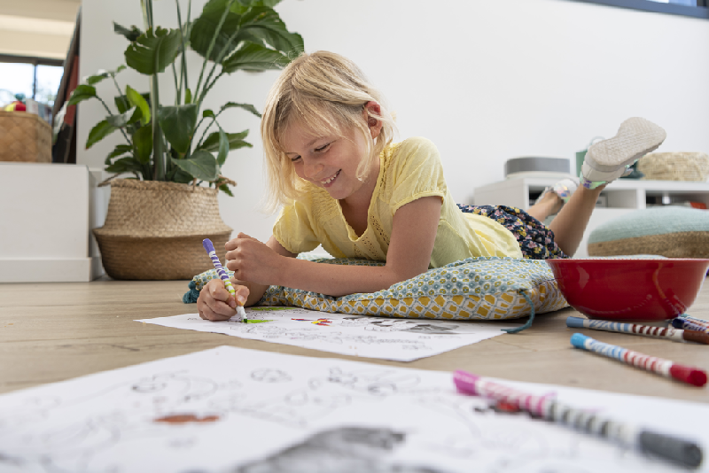 a girl lying on the floor colouring