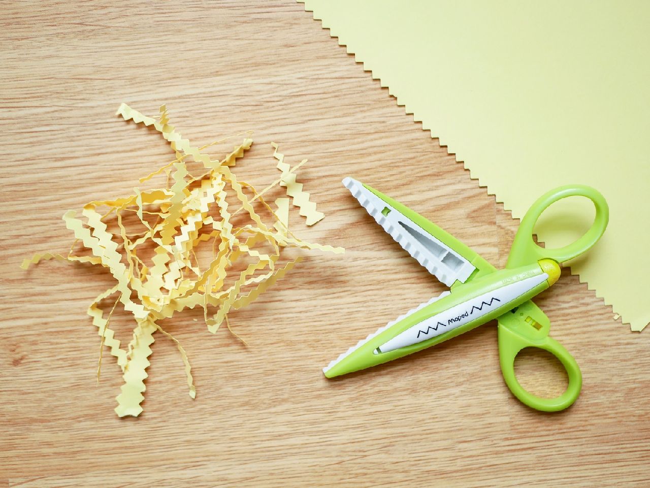 a pair of craft scissors sitting next to shredded paper
