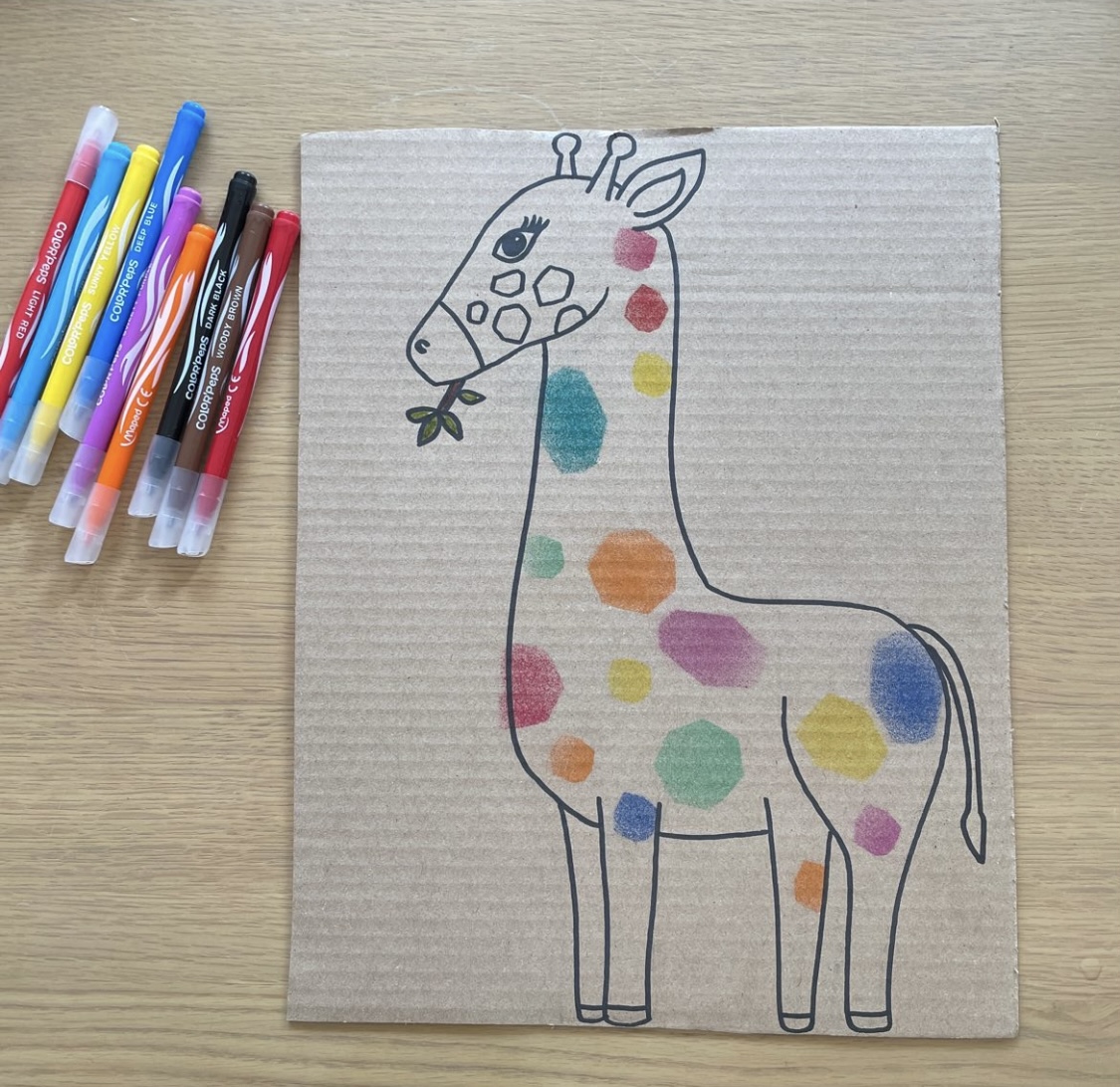 A rainbow giraffe made with blow pens lay on the left hand side