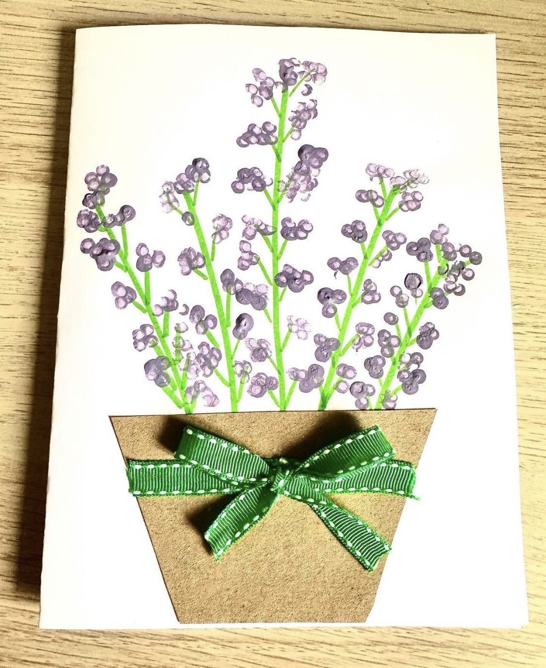 painted purple flowers in a pot with a green bow