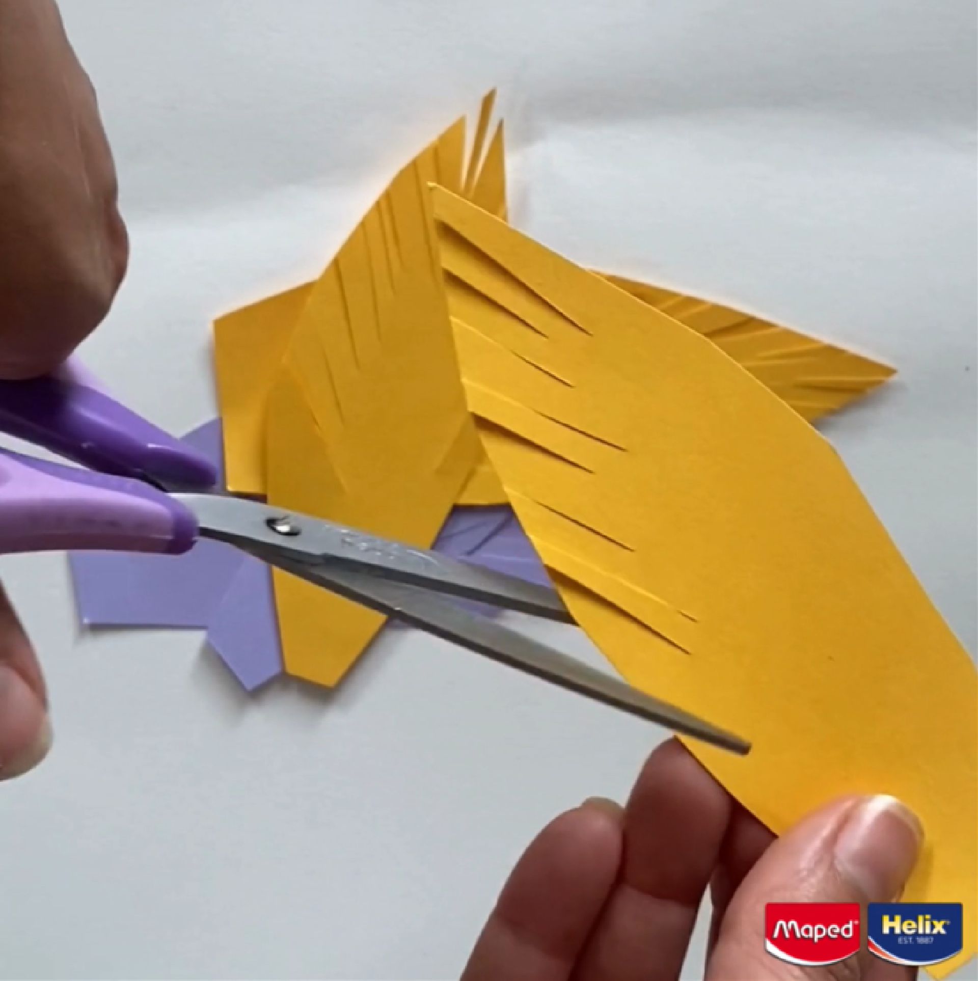 scissors cutting into coloured paper to create a feathered effect