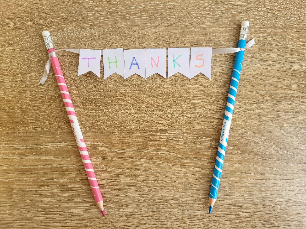 2 pencils with bunting spelling out thanks in between