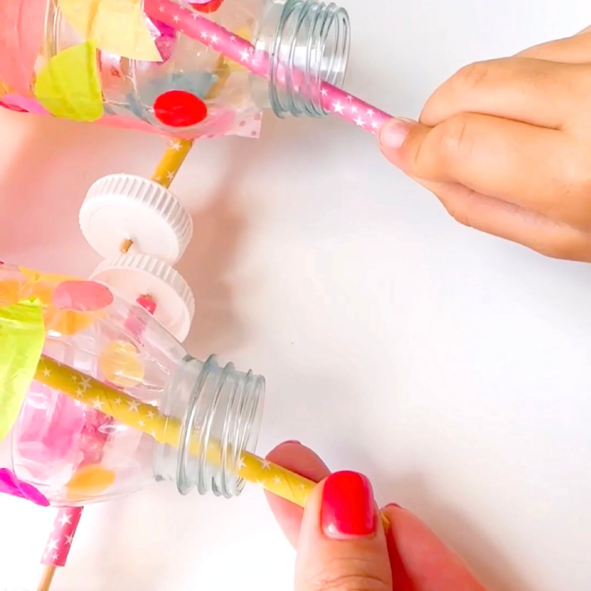 A hand threading a paper straw through the neck of a plastic bottle