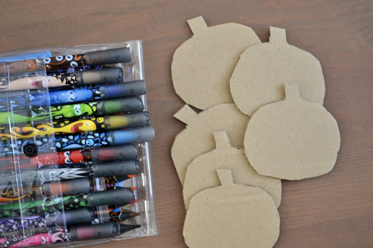 A pile of pumpkin shapes cut out from card laying next to some felt tip pens