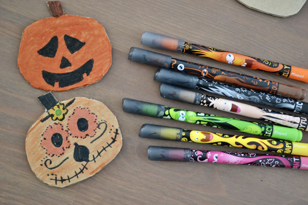 Some decorated card pumpkins laying next to some felt tip pens