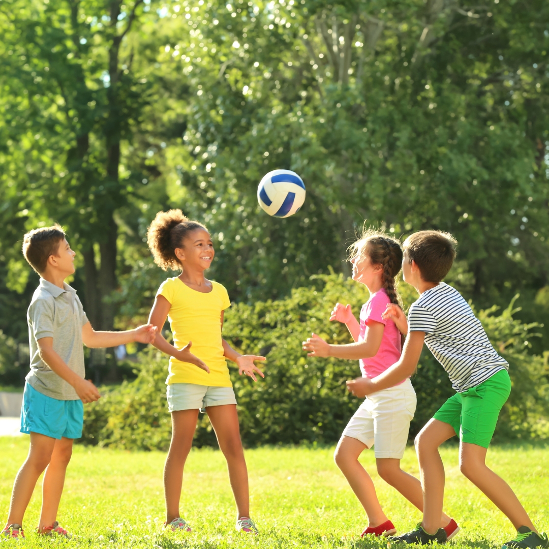 young children playing football in the park